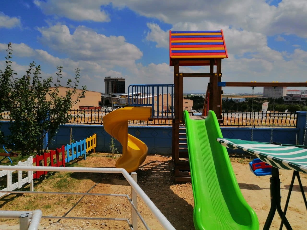 Bahçedeki oyun parkı: yeşil kaydırak ve ahşap oyun evi